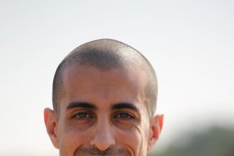 man in shirt using computer and smiling while working in the office